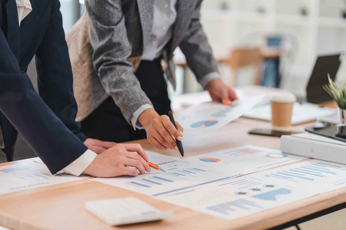 Two business professionals reviewing government contracting data and pricing analysis side by side