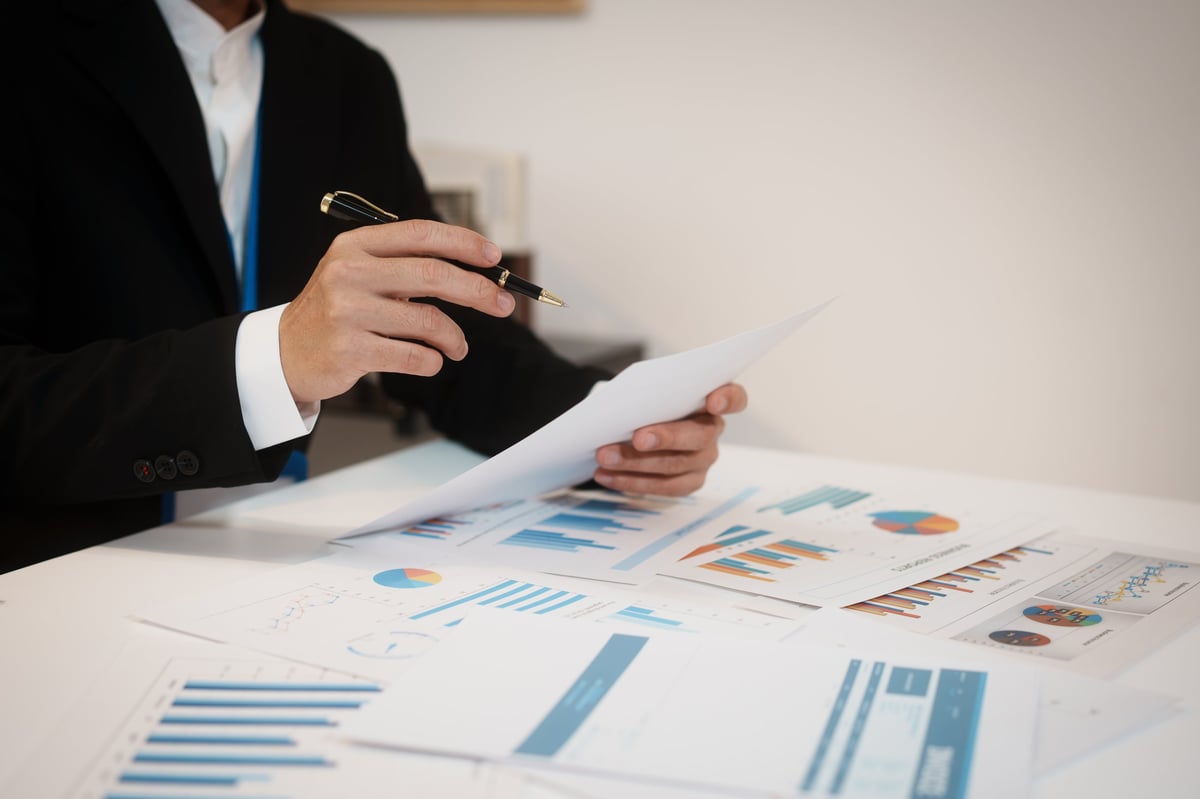 Business professional reviewing government contracting reports and analysis documents at an office desk